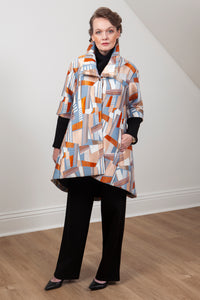 woman wearing the Grace coat by Lennard Taylor in the Orange Lightning print with hand in pocket. Front view.