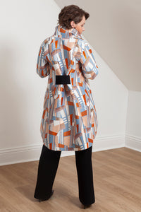 woman wearing the Grace coat by Lennard Taylor in the Orange Lightning print with hand in pocket. back view.