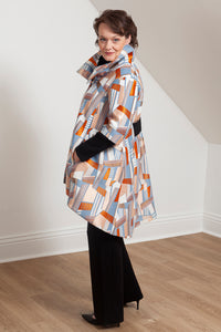 woman wearing the Grace coat by Lennard Taylor in the Orange Lightning print with hand in pocket. side view.