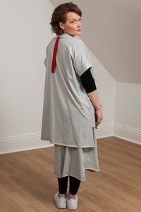 woman wearing a grey asymmetrical tunic with accent pocket - side/back view 