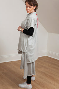 woman wearing a grey asymmetrical tunic with accent pocket - side view 